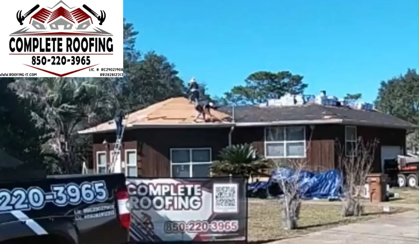 Complete Roofing branded yard sign in front of a Gulf Breeze waterfront home with crew tearing off the hip roof